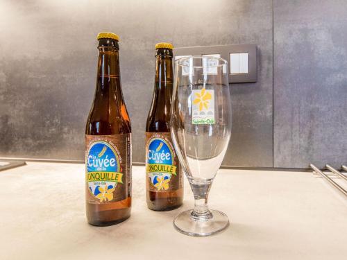 two bottles of beer sitting next to a glass at Modern Holiday Home in Lavacherie in Sainte-Ode