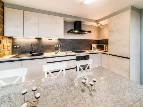 a kitchen with white cabinets and a table and chairs at Modern Holiday Home in Lavacherie in Sainte-Ode