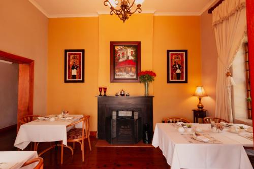 a dining room with two tables and a fireplace at 88 Baron van Reede Guesthouse in Oudtshoorn