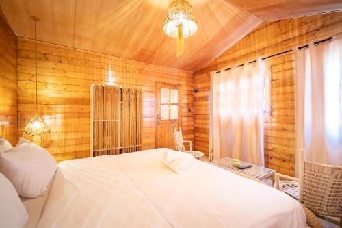a bedroom with a white bed and wooden walls at Lakala Complexe Touristique in O Ben Slimane
