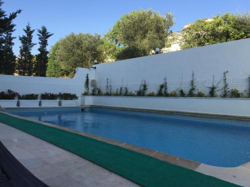 a swimming pool in a backyard with a white fence at Cicek Apart Hotel in Çeşme