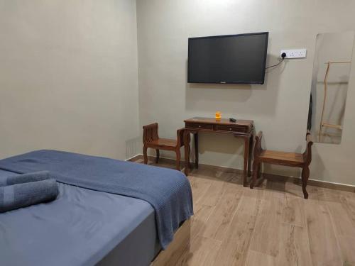 a bedroom with a bed and a desk with a flat screen tv at Embun Lodg in Temerloh