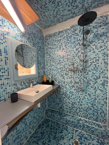 a blue tiled bathroom with a sink and a shower at chalet proche des plages in Arès
