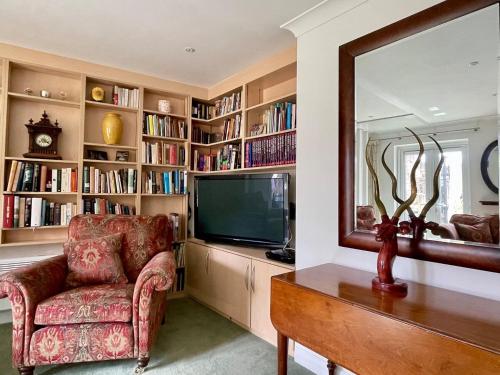 a living room with a tv and a chair and a mirror at Farnham Haven: Unique Home with Courtyard in Farnham