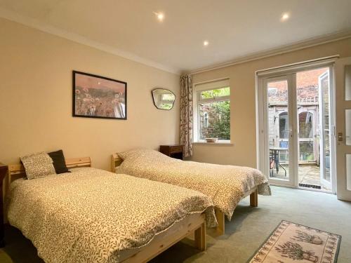 a bedroom with two beds and a window at Farnham Haven: Unique Home with Courtyard in Farnham