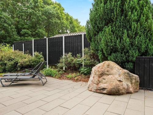 a bench and a large rock next to a fence at 4 star holiday home in Aabenraa in Aabenraa