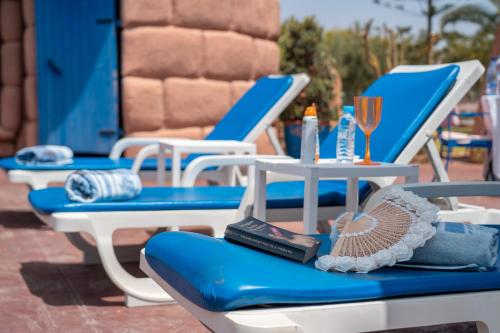 two blue and white chairs and a table with a glass of wine at Lakala Complexe Touristique in O Ben Slimane