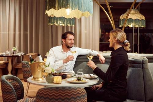a man and a woman sitting at a table drinking wine at Van der Valk Hotel Sassenheim - Leiden in Sassenheim