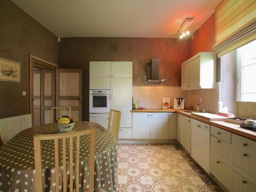 eine Küche mit einem Tisch und weißen Schränken in der Unterkunft Rustic Charm, Modern Comfort in Latour