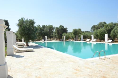 a swimming pool in a resort with trees in the background at Agriturismo Masseria San Leonardo in Savelletri di Fasano