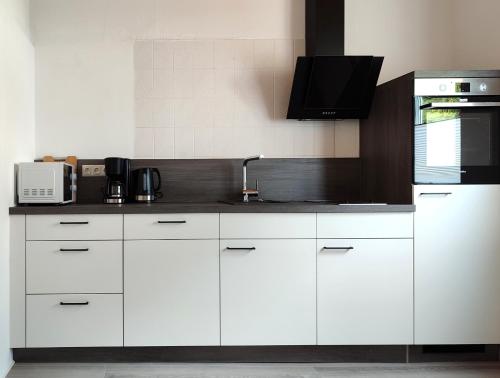 a kitchen with white cabinets and a sink at Gästehaus Herda in Briedel