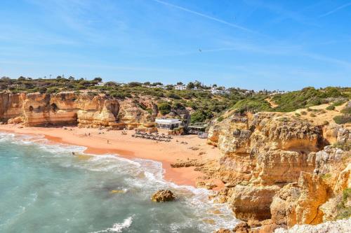 a view of a beach with people on it at Beach villa Casa de Amanhã 450 mts to the beach with beautiful garden and heated saltwater pool in Albufeira