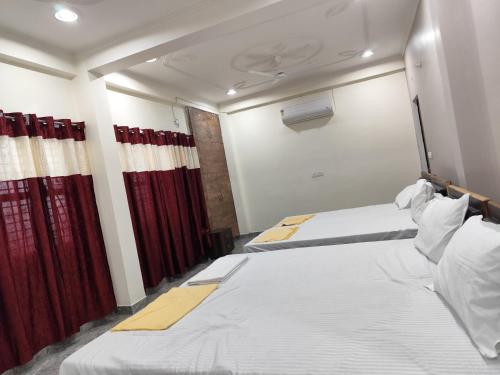 two beds in a room with red curtains at Royal Rudraksh Palace in Varanasi