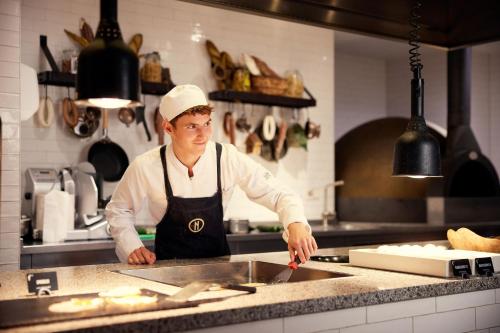 a man standing in a kitchen preparing food at Van der Valk Hotel Sassenheim - Leiden in Sassenheim
