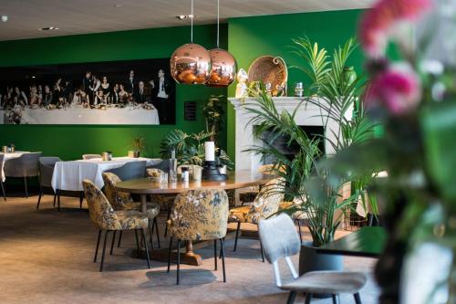 a restaurant with a table and chairs and green walls at Van der Valk Hotel Sassenheim - Leiden in Sassenheim
