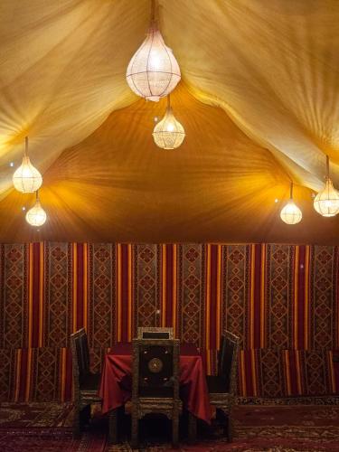 a dining room with a table and two lights at Luxury Desert Queen Camp in Merzouga