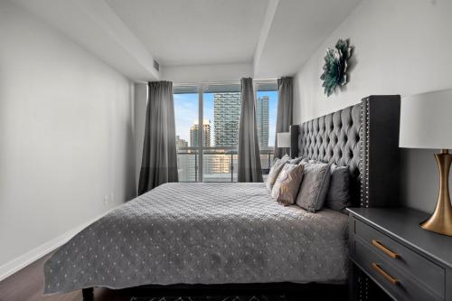 een slaapkamer met een bed en een groot raam bij Modern 1Bd & Den Condo with Balcony Lillian St in Toronto