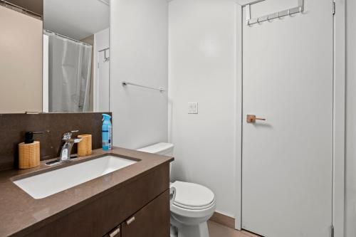 een badkamer met een wastafel, een toilet en een spiegel bij Modern 1Bd & Den Condo with Balcony Lillian St in Toronto
