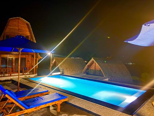 a swimming pool with two chairs and an umbrella at Bali Cottages Lake View in Kintamani
