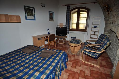 a bedroom with a bed and chairs and a tv at Penzion Na Hradbách in Louny