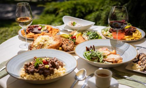 a table with plates of food and glasses of wine at Regia Panzió in Halászi