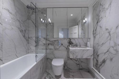 a white bathroom with a tub and a toilet and a sink at Super Lux 3 Bed Apartment by Mayfair in London