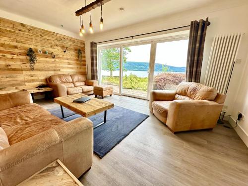 Elle comprend un salon doté d'un mobilier en cuir et d'une grande fenêtre. dans l'établissement Avenue Cottage, Inveraray, à Inveraray