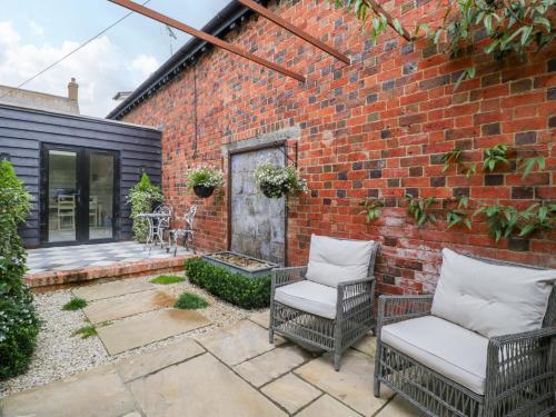 a patio with two chairs and a brick wall at The Sty in Cirencester