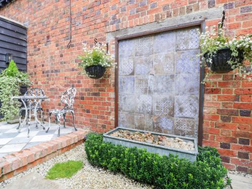 a brick wall with two chairs and a table at The Sty in Cirencester