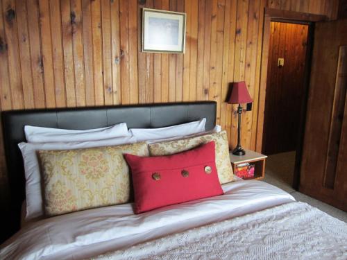 a bed with a red pillow on top of it at The Surf Lodge and Pub in Gabriola
