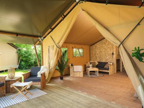 a tent with a living room and a patio at Slow Living bij Mölke X Glamping in Zuna