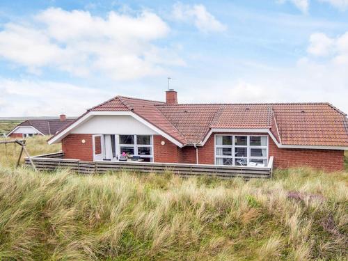 a red brick house on the side of a field at 5 star holiday home in Ringkøbing in Ringkøbing