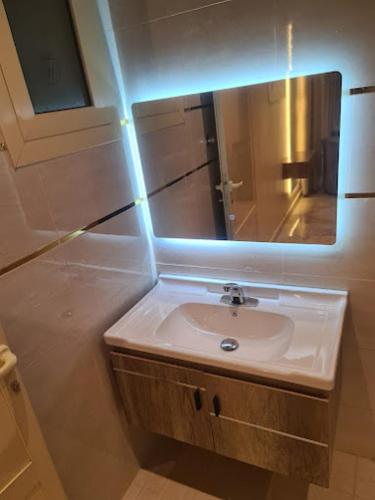 a bathroom with a sink and a mirror at Dani Serviced Apartments in Buqayq