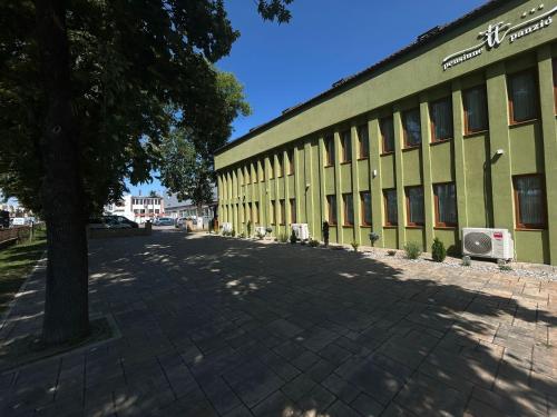 a green building with a tree in front of it at Casa TT House in Sfântu-Gheorghe