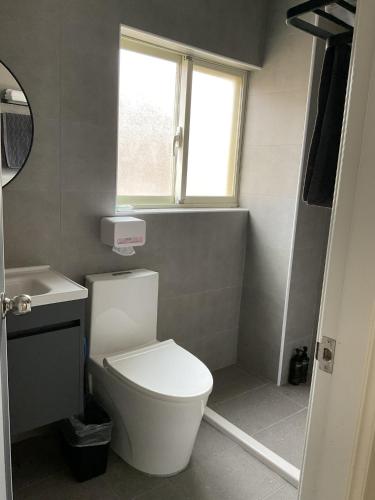 a bathroom with a toilet and a sink and a window at Horn Seaside Homestay in Nangan
