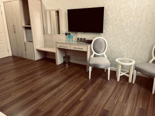 a room with a desk with a television and two chairs at Empire Boutique Hotel Baku in Baku