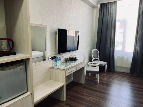 a room with a television and a desk with a mirror at Empire Boutique Hotel Baku in Baku