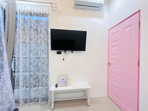a room with a tv and a door and a table at Hatyai city habibi home 1 in Sathani Hat Yai