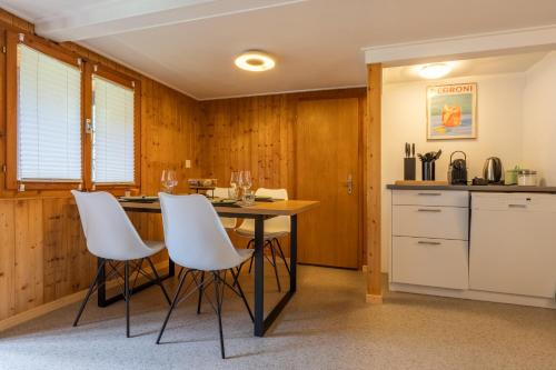 a kitchen with a table and white chairs at Lovely & great equipped wooden Alp Chalet flat in Kandersteg
