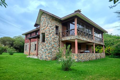 a large stone house with a balcony on a lawn at Charity Chalet in Naivasha