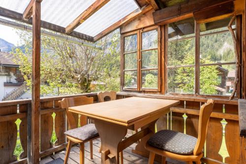 a wooden table and chairs on a porch with windows at Lovely & great equipped wooden Alp Chalet flat in Kandersteg