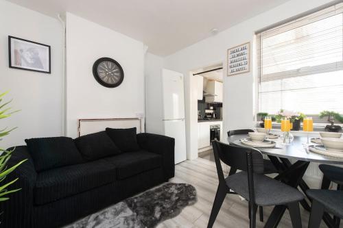a living room with a black couch and a table at Comfort Meets Style, 4-Bedroom Home with All Essentials, Croydon, Sleeps 8! Contractor Friendly! in Thornton Heath