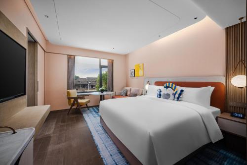 a large white bed in a room with a window at voco Xitang by IHG in Jiaxing