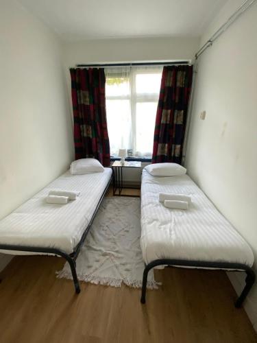 two beds in a small room with a window at Stee in Stad in Groningen