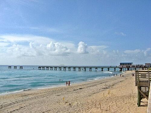 a beach with a pier and people in the water at Charming home near art & culture in Greenacres City