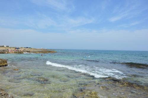 a beach with people swimming in the ocean at Agriturismo Masseria San Leonardo in Savelletri di Fasano