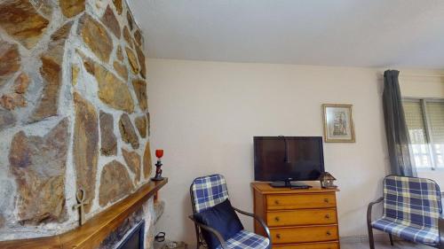 a living room with a stone fireplace and two chairs at Chalet BS in Albalate de Zorita