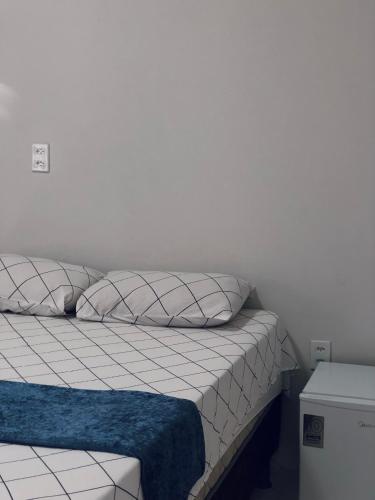 ein Bett mit zwei Kissen und einer blauen Decke darauf in der Unterkunft Chalé Casa Moitas in Amontada