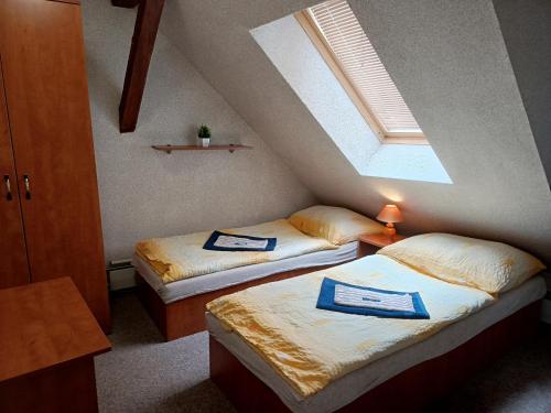 two twin beds in a room with a window at Penzion U Potoka in Nezdice
