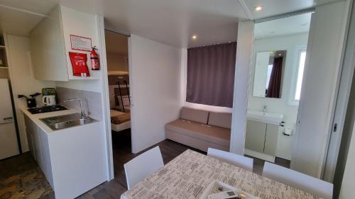 a small white kitchen with a sink and a table at Camping La Rocca in Manerba del Garda